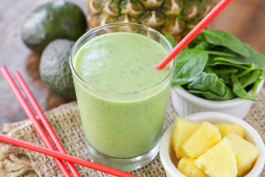 This quick and easy 5 minute Best Green Smoothie Recipe is fresh and YUMMY! It is filled with fruit goodness & vitamin-rich spinach. Fresh green smoothie served in a glass with a red straw