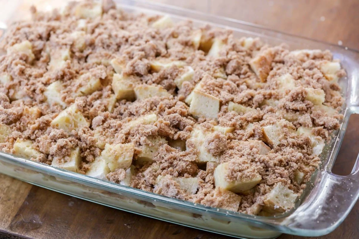 Cubes of bread topped with brown sugar mixture in a glass baking dish.