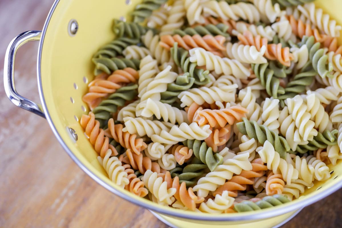 Draining rotini pasta in a yellow colandar.