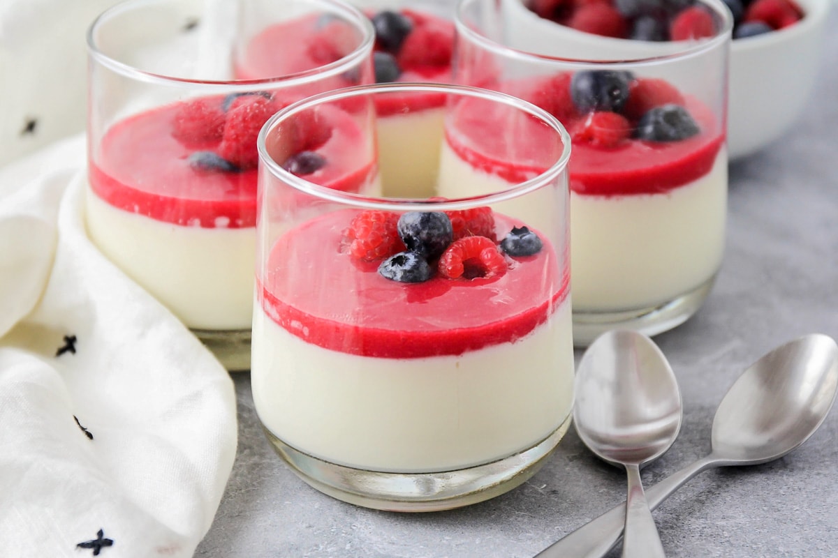 This silky and creamy vanilla panna cotta recipe is a showstopper dessert sure to turn heads, but is quite easy to make! Raspberry sauce a top a vanilla panna cotta recipe topped with fresh berries.