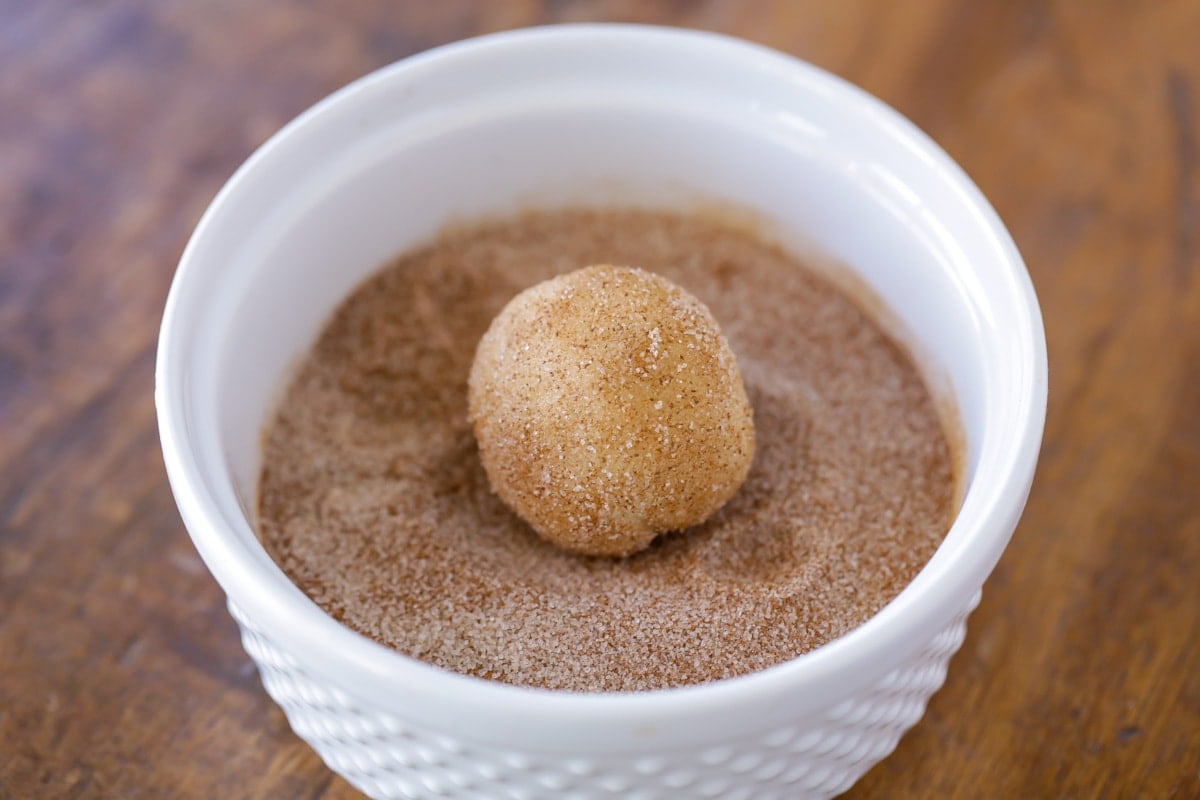 Rolling snickerdoodle dough balls in cinnamon mixture.