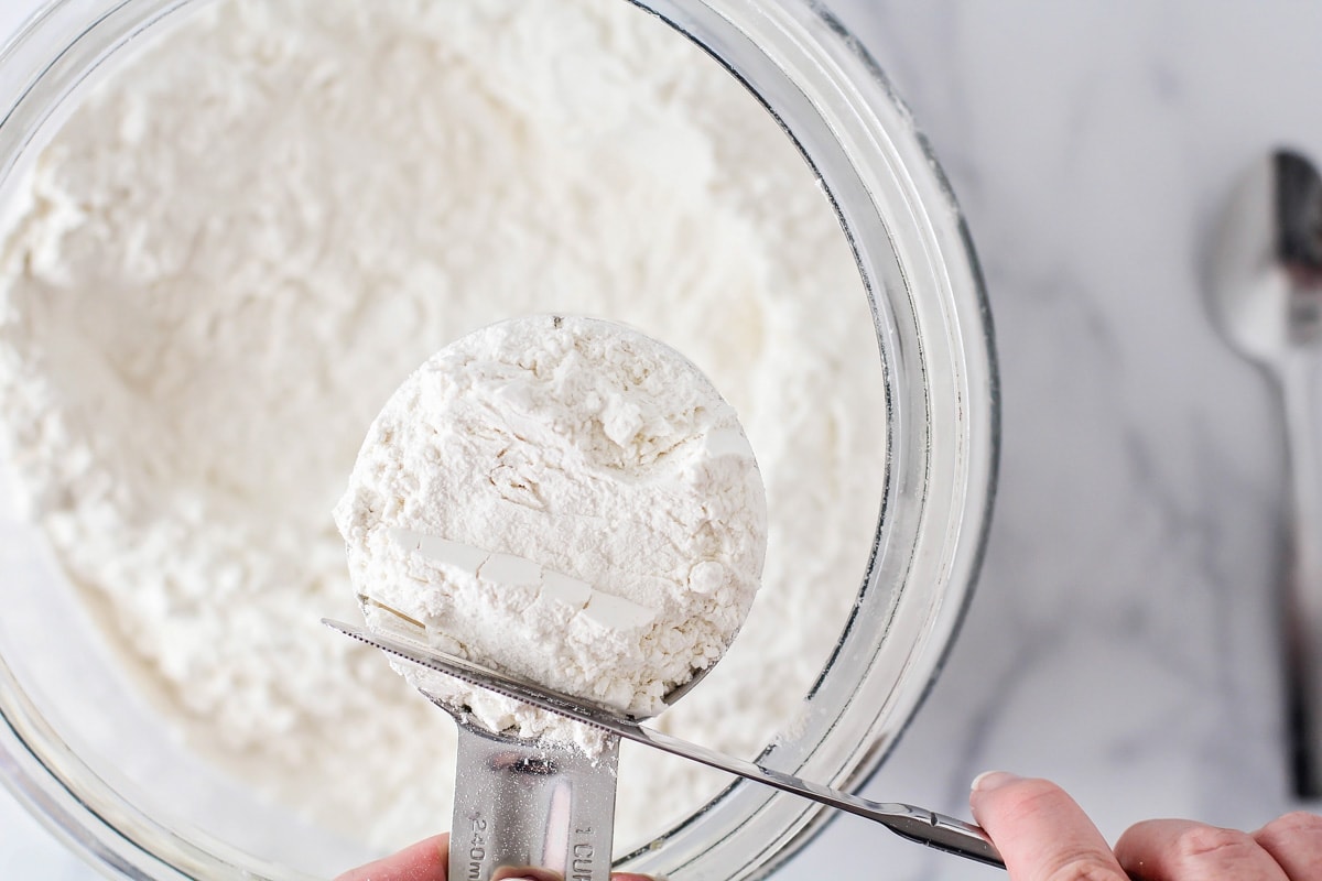 Leveling off a measuring cup of flour.