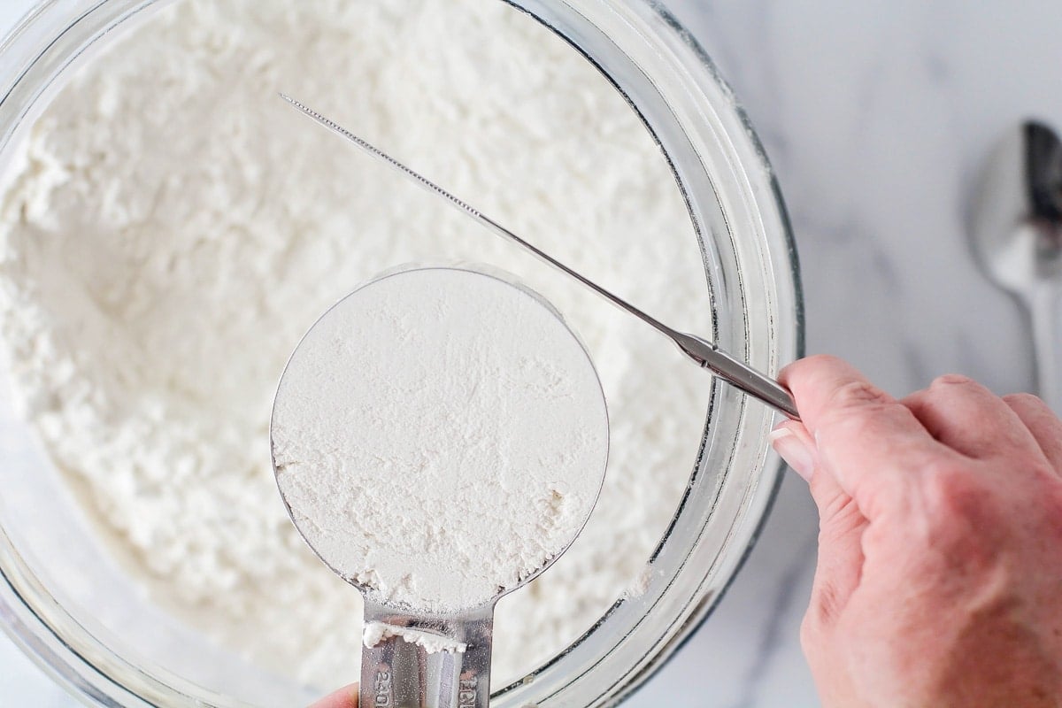 Using a knife to level off a cup of flour.