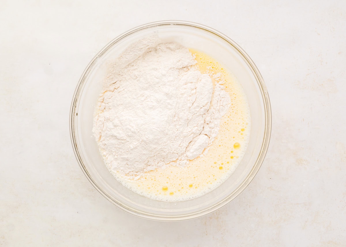Adding wet ingredients to the dry ingredients in a glass bowl.